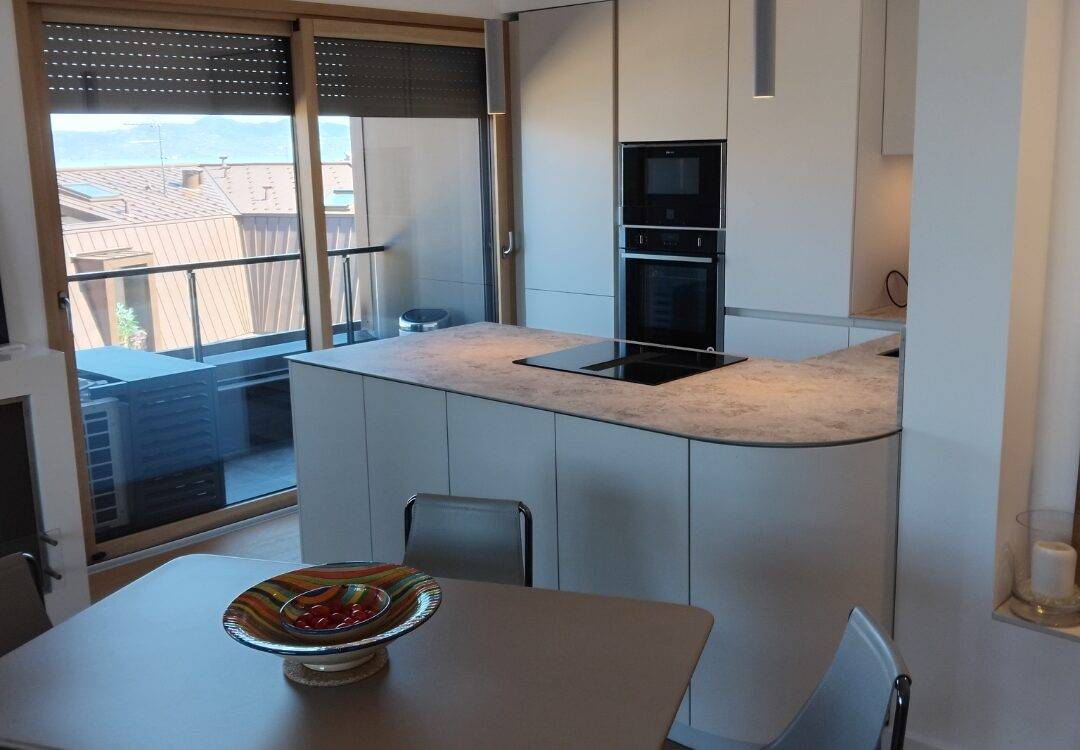 Nouvelle réalisation à Evian : Cuisine Matera blanc coquille, poignées gorge blanc coquille, plan de travail compact noir Thann